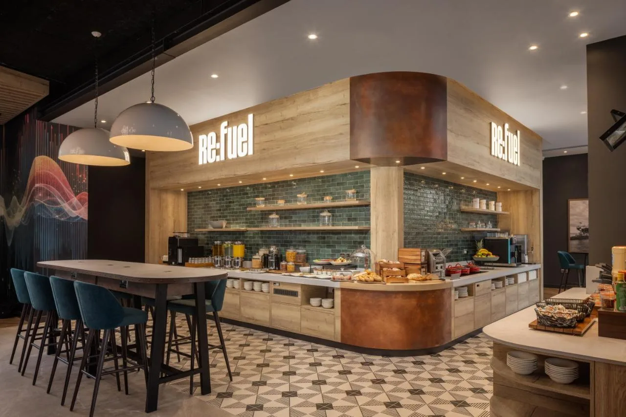 a restaurant with a counter with chairs and a table at Aloft by Marriott Belfast Titanic Quarter in Belfast