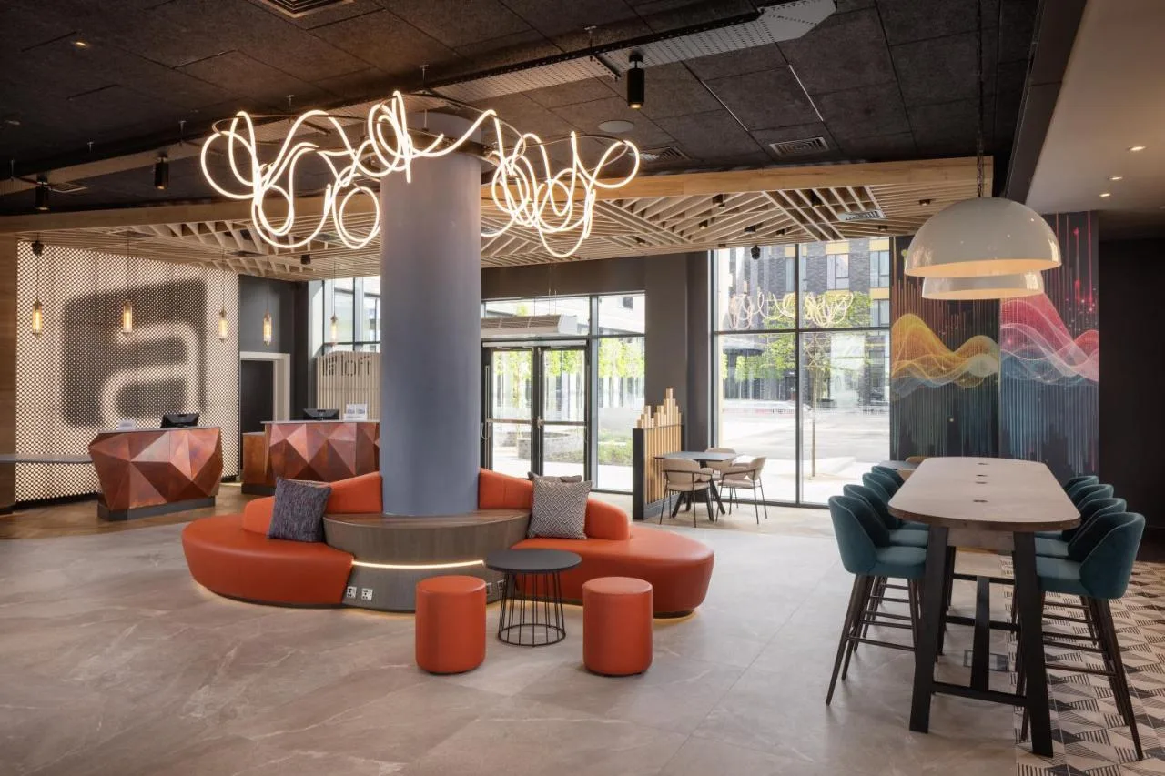 a lobby with a couch and tables and a chandelier at Aloft by Marriott Belfast Titanic Quarter in Belfast