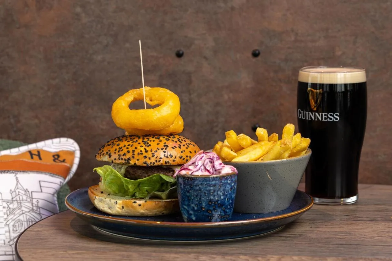 a plate with a hamburger and french fries and a drink at Aloft by Marriott Belfast Titanic Quarter in Belfast